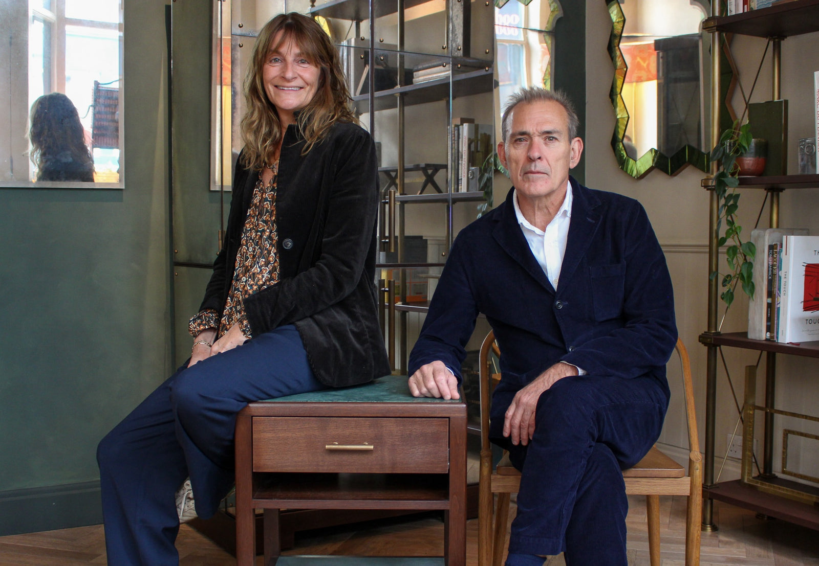 Two people sitting in a room with wooden furniture and decor.