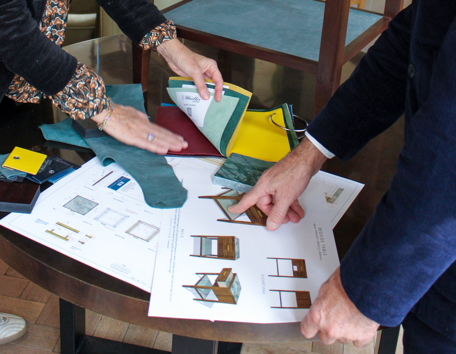 Two people discussing design samples on a table.