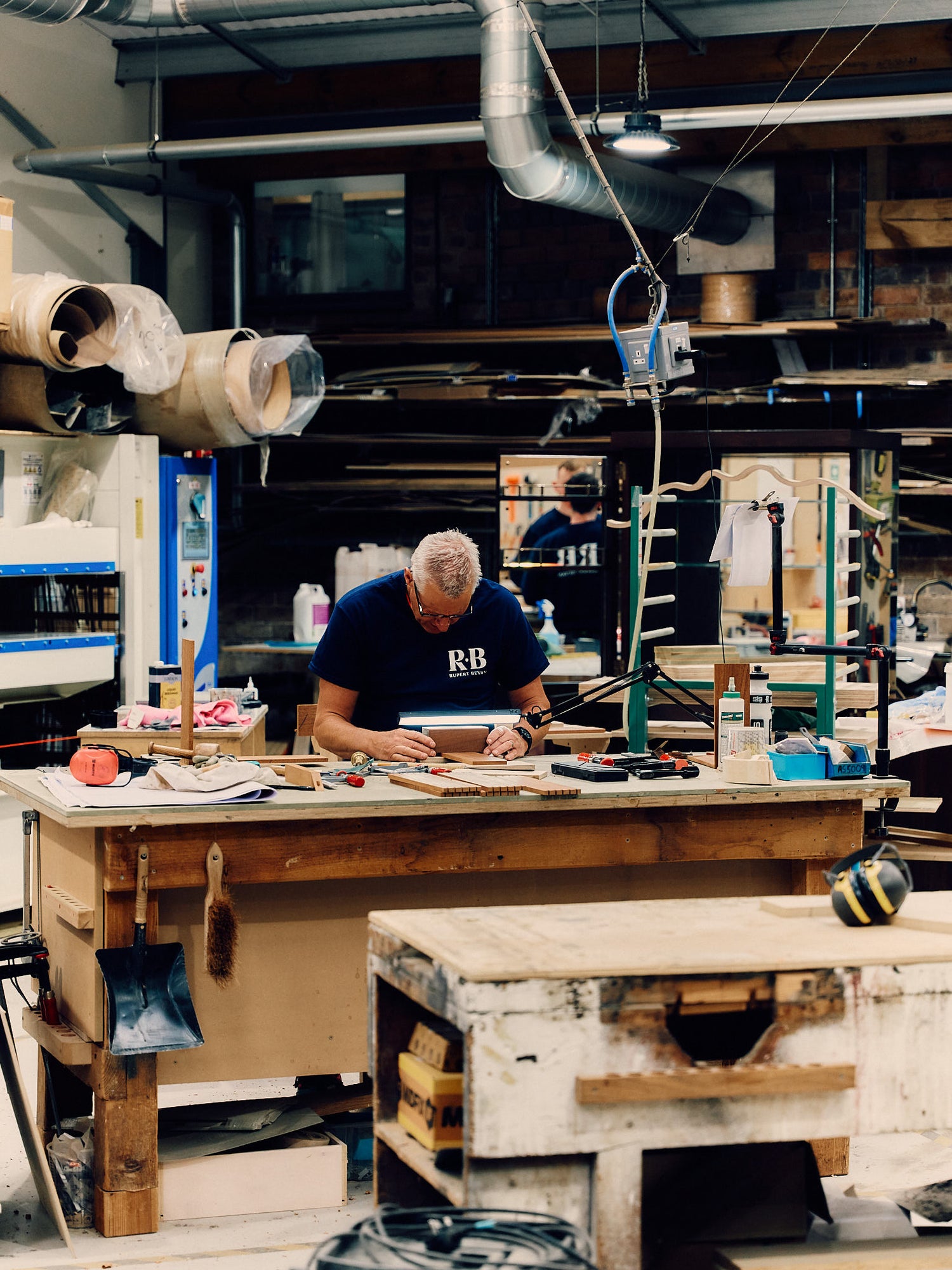 Man working in a wood workshop with tools and materials around.