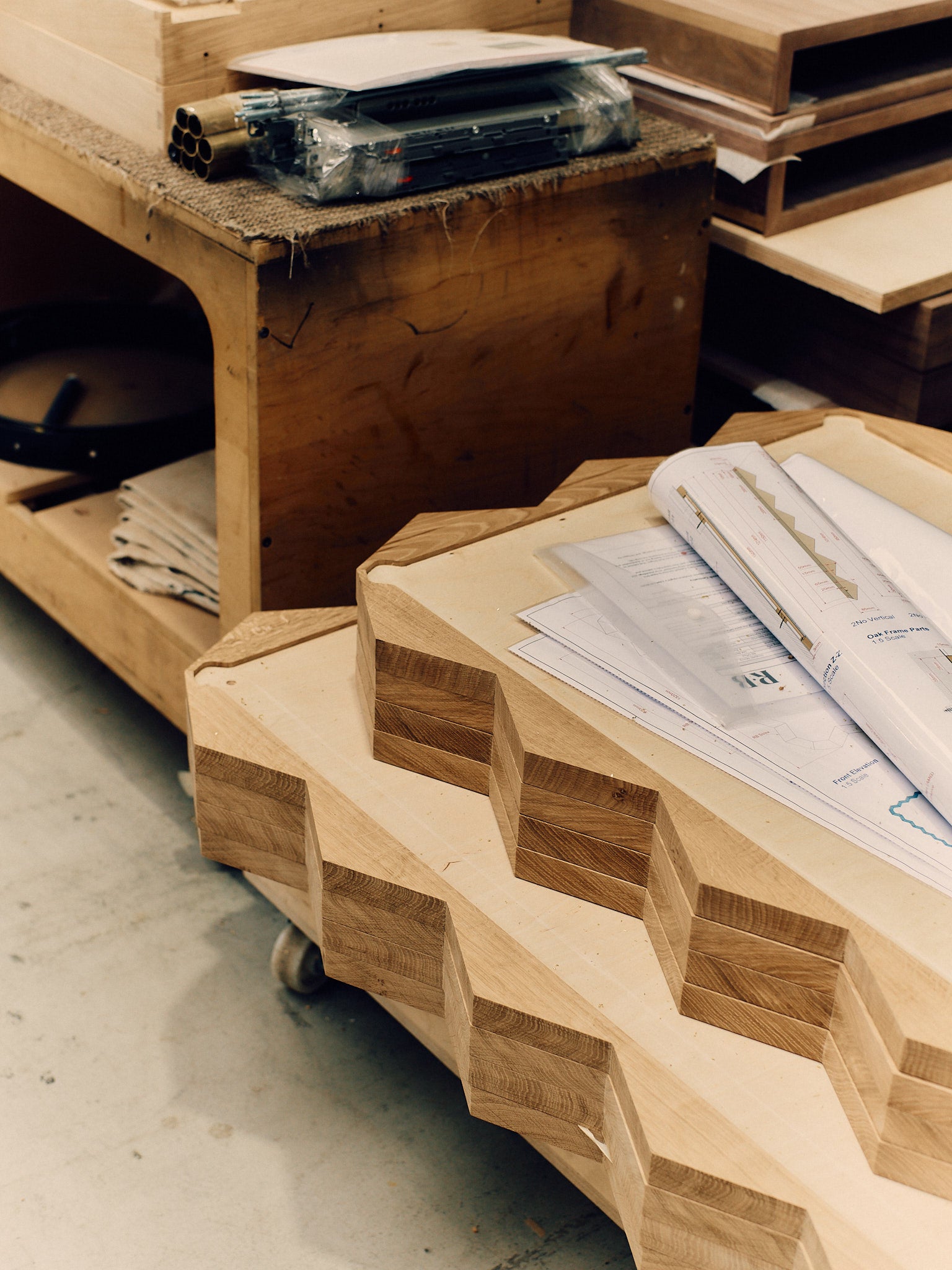 Wooden furniture pieces with design drawings on a concrete floor.
