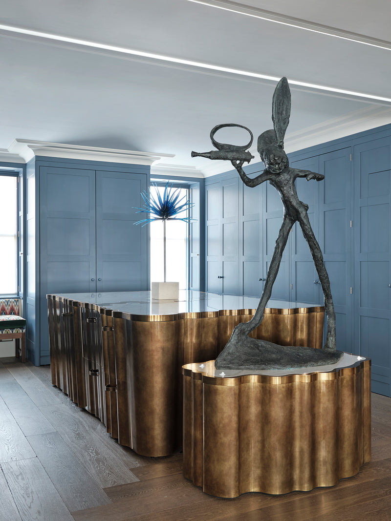 Bronze sculpture on a curved bronze kitchen island in a modern kitchen setting.