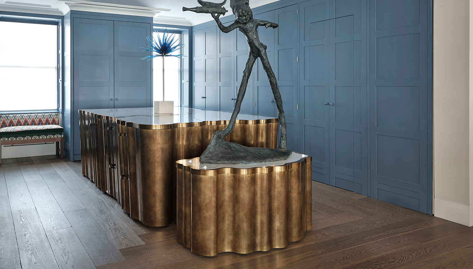 Bronze sculpture on a curved bronze kitchen island in a modern kitchen setting.