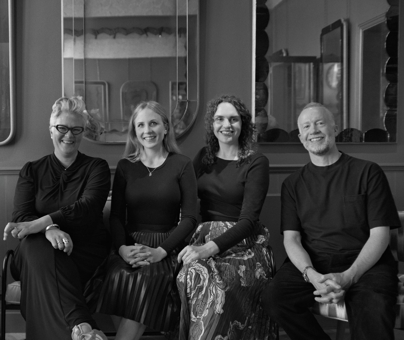Four people sitting together with decorative elements in the background.