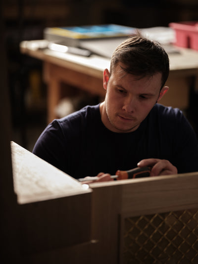 Man in a workshop setting holding tools.