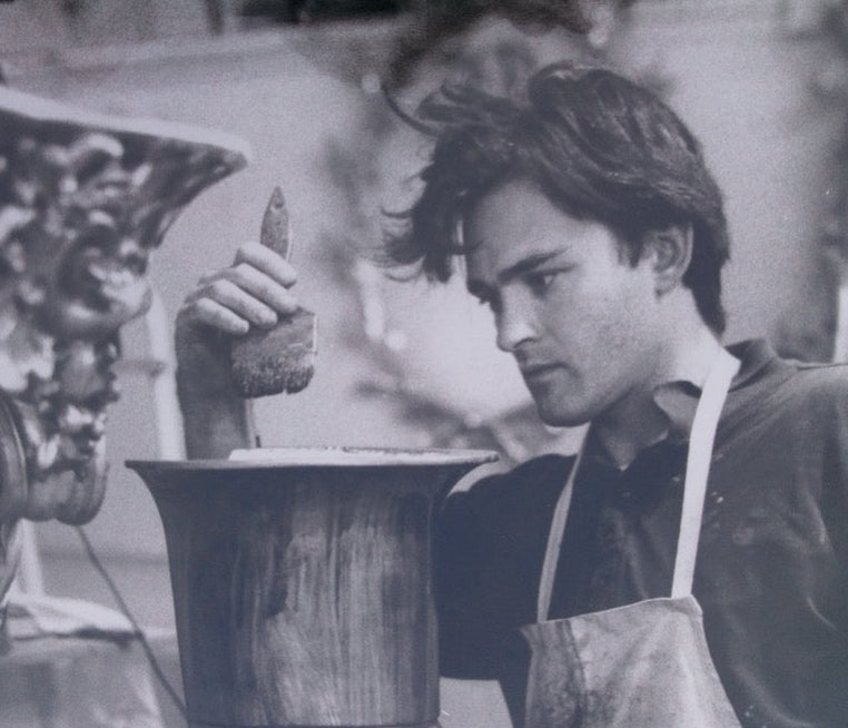 Person wearing an apron working with a tool in a workshop setting.